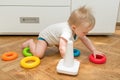 Cute adorable caucasian baby child boy playing colorful pyramid toy at home. Happy child having fun building tower of plastic Royalty Free Stock Photo