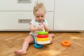 Cute adorable caucasian baby child boy playing colorful pyramid toy at home. Happy child having fun building tower of plastic Royalty Free Stock Photo