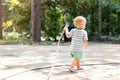 Cute adorable caucasian blond barefeet boy walking at home backyard holding hose pipe for watering garden. Child little Royalty Free Stock Photo