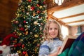 Cute adorable caucasian blond female kid read fairytale story book, dream and sit on sofa with warm plaid near decorated