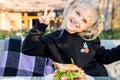 Cute adorable caucasian blond kid girl enjoy eating hamburger with ham and fresh vegeatables at cafe on bright sunny day outdoors Royalty Free Stock Photo