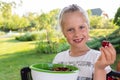 Cute adorable caucasian blond litlle school girl enjoy eating healthy ripe tasty juicy dark red cherry in green bowl at