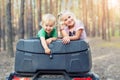 Cute adorable caucasian blond siblings having fun during atv 4x4 off-road adventure trip amog coniferous pine forest on brigh Royalty Free Stock Photo
