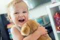 Cute adorable caucasian blond toddler boy having fun, laughing and hugging soft puppy toy indoors. Cheerful child playing with Royalty Free Stock Photo