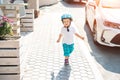 Cute adorable caucasian blond toddler boy in helmet walking at city street going to ride bicycle ot scooter on bright Royalty Free Stock Photo