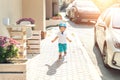 Cute adorable caucasian blond toddler boy in helmet walking at city street going to ride bicycle ot scooter on bright Royalty Free Stock Photo
