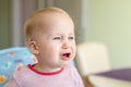 Cute adorable caucasian blond toddler boy sitting in high chair and crying while feeding. Upset unhappy child refuse to eat Royalty Free Stock Photo