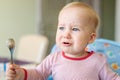 Cute adorable caucasian blond toddler boy sitting in high chair and crying while feeding. Upset unhappy child refuse to eat Royalty Free Stock Photo