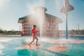 Cute adorable Caucasian funny girl playing on splash pad playground on summer day. Happy child having fun in water. Seasonal water Royalty Free Stock Photo