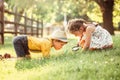 Cute adorable Caucasian girl and boy looking at plants grass in park through magnifying glass Royalty Free Stock Photo