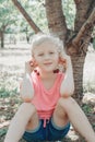 Cute adorable Caucasian girl making earring from cherry. Kid picking eating berries on farm. Happy farmer gather seasonal cherry