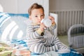 Cute adorable Caucasian kid boy sitting on bed drinking milk from kids bottle. Healthy eating drinking for children. Supplementary