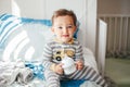 Cute adorable Caucasian kid boy sitting on bed drinking milk from kids bottle. Healthy eating drinking for children. Supplementary Royalty Free Stock Photo