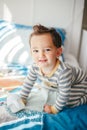 Cute adorable Caucasian kid boy sitting on a bed drinking milk from kids bottle. Healthy eating drinking for little children. Royalty Free Stock Photo