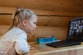 Cute adorable caucasian little blond girl siiting at desk with laptopn during online video chat scholl lesson session with teacher