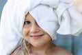 Cute adorable caucasian little blond girl wearing white towel on we head after shower or bathing at bathroom. Portrait