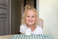 Cute adorable caucasian little funny blond girl eating yogurt or milk cottage cheese for lunch snack. Child enjoy eating