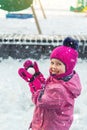 Cute adorable caucasian little girl winter portrait holding snowball in hands ready for snow fight at playground outdoor. Funny Royalty Free Stock Photo