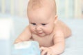 Cute adorable caucasian little 5 month old infant baby boy lying on tummy at nursery bed room having fun playing and Royalty Free Stock Photo