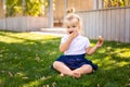 Cute adorable Caucasian toddler baby girl sitting and eating berries fruits. Funny child in park having healthy snack meal. Summer Royalty Free Stock Photo