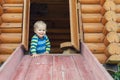 Cute adorable caucasian toddler boy having fun sliding down wooden slide at eco-friendly natural playground at backyard in autumn Royalty Free Stock Photo