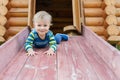 Cute adorable caucasian toddler boy having fun sliding down wooden slide at eco-friendly natural playground at backyard in autumn Royalty Free Stock Photo