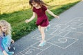 Cute adorable children girls friends playing jumping hopscotch outdoors. Funny activity game for kids on playground outside. Royalty Free Stock Photo