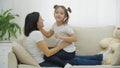 Cute adorable daughter and young mum playing on sofa at home.