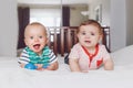 Cute adorable funny baby boys lying together on bed sharing toy