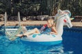 Cute adorable girl in sunglasses with drink lying on inflatable ring unicorn. Kid child enjoying having fun in swimming pool. Royalty Free Stock Photo