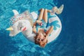 Cute adorable girl in sunglasses with drink lying on inflatable ring unicorn. Kid child enjoying having fun in swimming pool. Royalty Free Stock Photo