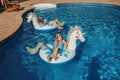 Cute adorable girls sisters friends with drinks lying on inflatable rings unicorns. Kids children siblings enjoying, relaxing,
