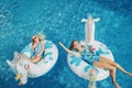 Cute adorable girls sisters friends with drinks lying on inflatable rings unicorns. Kids children siblings in sunglasses having
