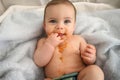 Cute adorable infant funny dirty baby trying to eat himself with fruit or vegetable puree smeared on his face. Baby Royalty Free Stock Photo