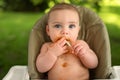 Cute adorable infant funny dirty baby trying to eat himself with fruit or vegetable puree smeared on his face. Baby Royalty Free Stock Photo