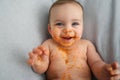 Cute adorable infant funny dirty baby trying to eat himself with fruit or vegetable puree smeared on his face. Baby Royalty Free Stock Photo