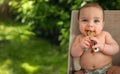 Cute adorable infant funny dirty baby trying to eat himself with fruit or vegetable puree smeared on his face. Baby Royalty Free Stock Photo