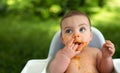 Cute adorable infant funny dirty baby trying to eat himself with fruit or vegetable puree smeared on his face. Baby Royalty Free Stock Photo