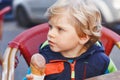 Cute adorable kid boy eating ice cream in outdoor cafe. Happy child on sunny day. Healthy toddler with sweet dessert in Royalty Free Stock Photo