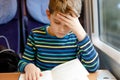 Cute adorable kid boy reading book during traveling by train. Happy child sitting near window. Family going on vacations Royalty Free Stock Photo