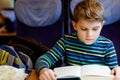 Cute adorable kid boy reading book during traveling by train. Happy child sitting near window. Family going on vacations Royalty Free Stock Photo