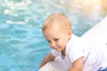 Cute adorable little caucasian blond smiling todller boy kid treing water temperature pool edge before swimming. Happy Royalty Free Stock Photo