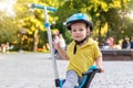 Cute adorable little caucasian toddler boy portrait in helmet having fun riding three-wheeled balance run bike scooter in city Royalty Free Stock Photo