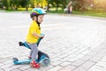 Cute adorable little caucasian toddler boy portrait in helmet having fun riding three-wheeled balance run bike scooter Royalty Free Stock Photo