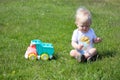 Cute adorable little child playing with toy car lorry on the green grass in the park Royalty Free Stock Photo