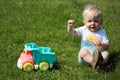 Cute adorable little child playing with toy car lorry on the green grass in the park Royalty Free Stock Photo