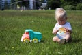 Cute adorable little child playing with toy car lorry on the green grass in the park Royalty Free Stock Photo