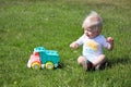 Cute adorable little child playing with toy car lorry on the green grass in the park Royalty Free Stock Photo