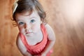 Cute, adorable and little girl standing while looking up with sweet face on wooden floor at home. Portrait of small girl Royalty Free Stock Photo