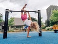 Cute adorable little preschool blonde Caucasian girl hanging upside down on pullup bar on playground. Royalty Free Stock Photo